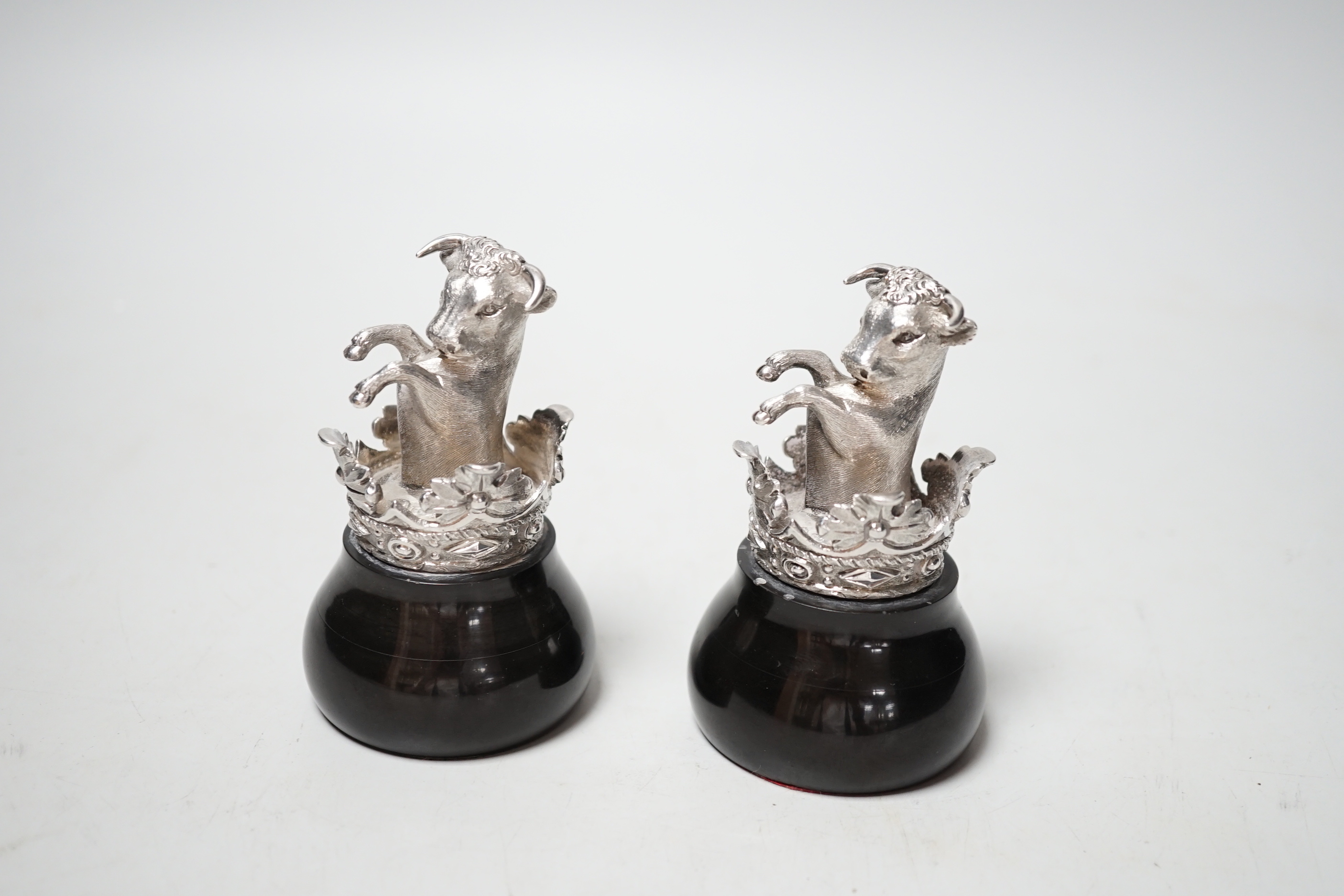 A pair of silver heraldic crests, modelled as rearing bull's within a coronet, on ebonised bases, probably copies of the pediments at Eridge Park, Kent, Mitchell Bosley & Co?, Birmingham, 1899, height 95mm.